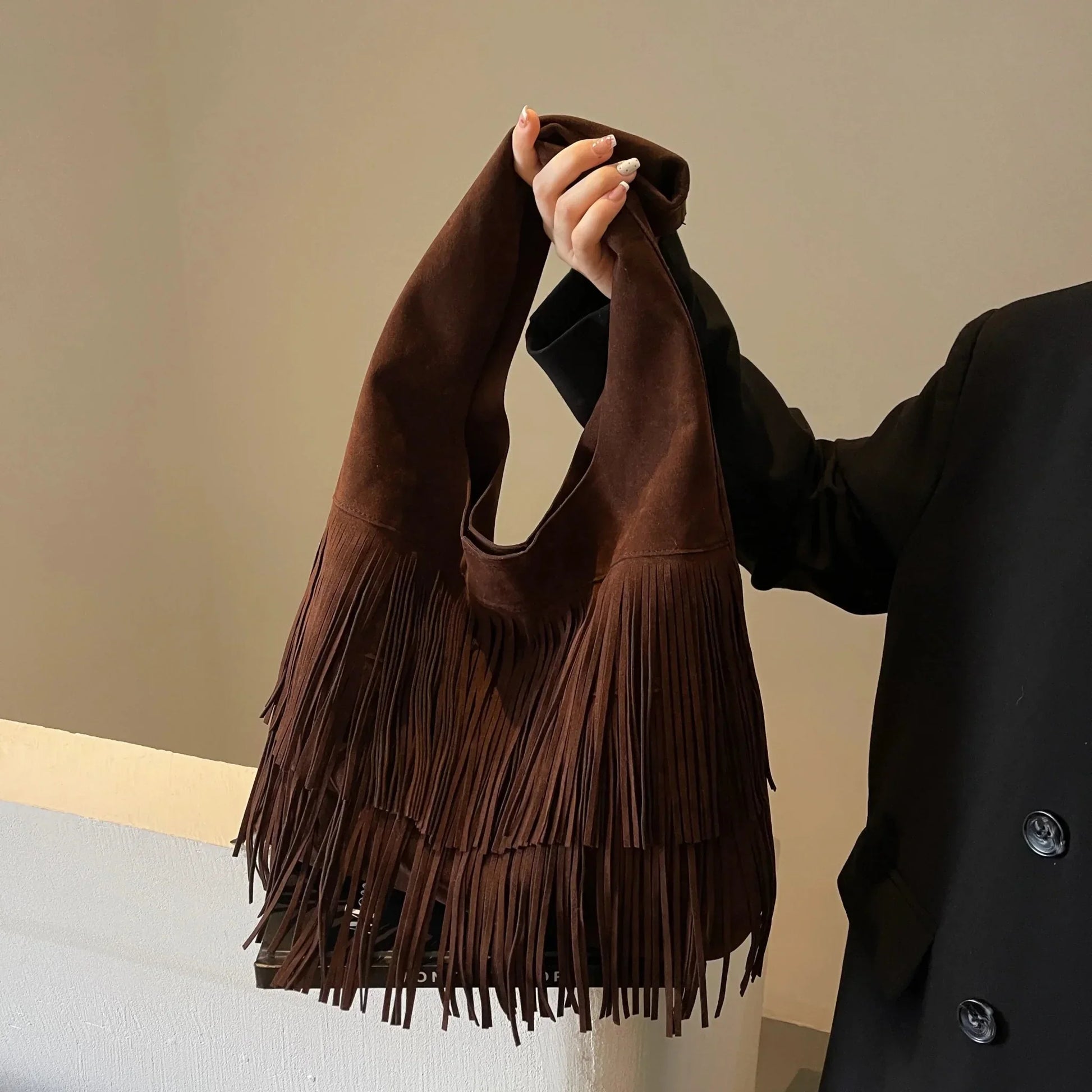 Dark brown retro leather shoulder bag with velvet tassels and large capacity, held by a person