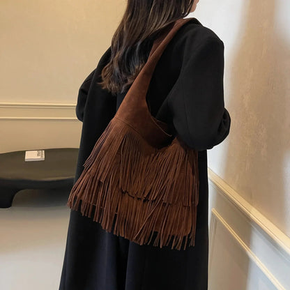 Woman wearing a large dark brown retro leather shoulder bag with fringe tassels
