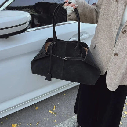 Large black vegan suede handbag with retro design, held by a woman in a coat outdoors