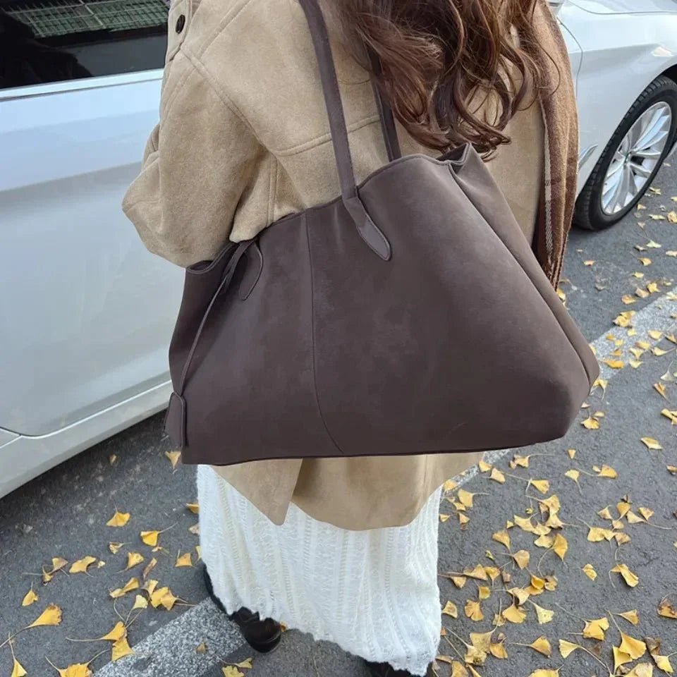 Woman holding large brown vegan suede handbag in retro style on autumn street