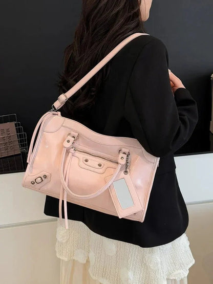 Woman holding a pastel pink stylish handbag with zipper details and top handles