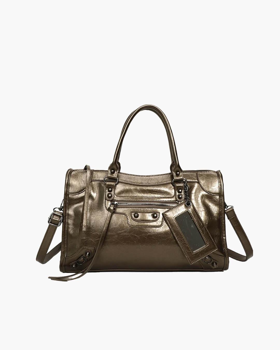 Dark brown minimalist handbag with top handles, front zipper pocket, and a luggage tag.