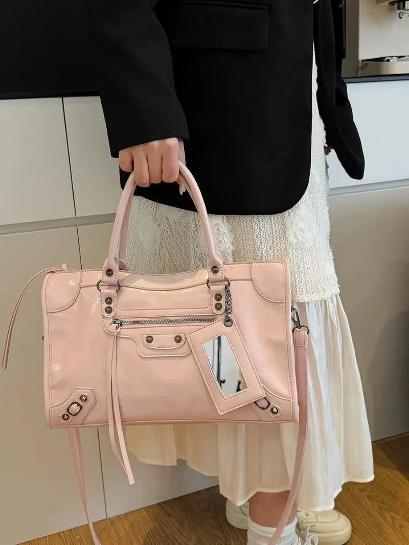 Woman holding a pink minimalist handbag with spacious interior and silver hardware details