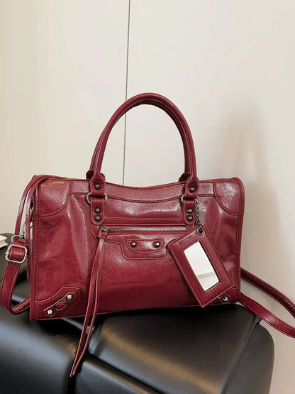 Red minimalist handbag with spacious interior, top handles, and silver hardware details