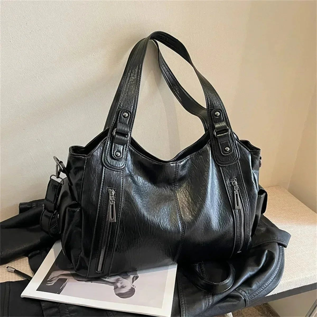 Black leather women's shoulder bag with multiple zippered pockets and double handles