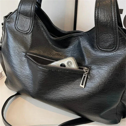 Black shoulder bag for women with spacious zip pocket holding a smartphone