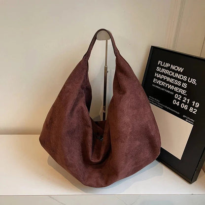 Coffee brown suede hobo handbag with zipper and large capacity on white table
