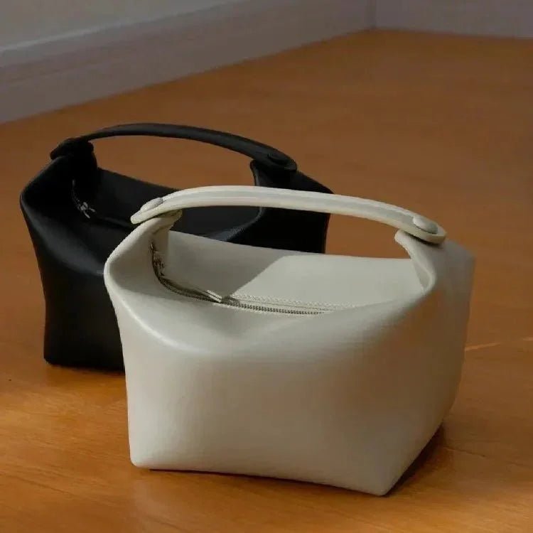 Two box-shaped genuine leather handbags, one black and one white, with unique top handles